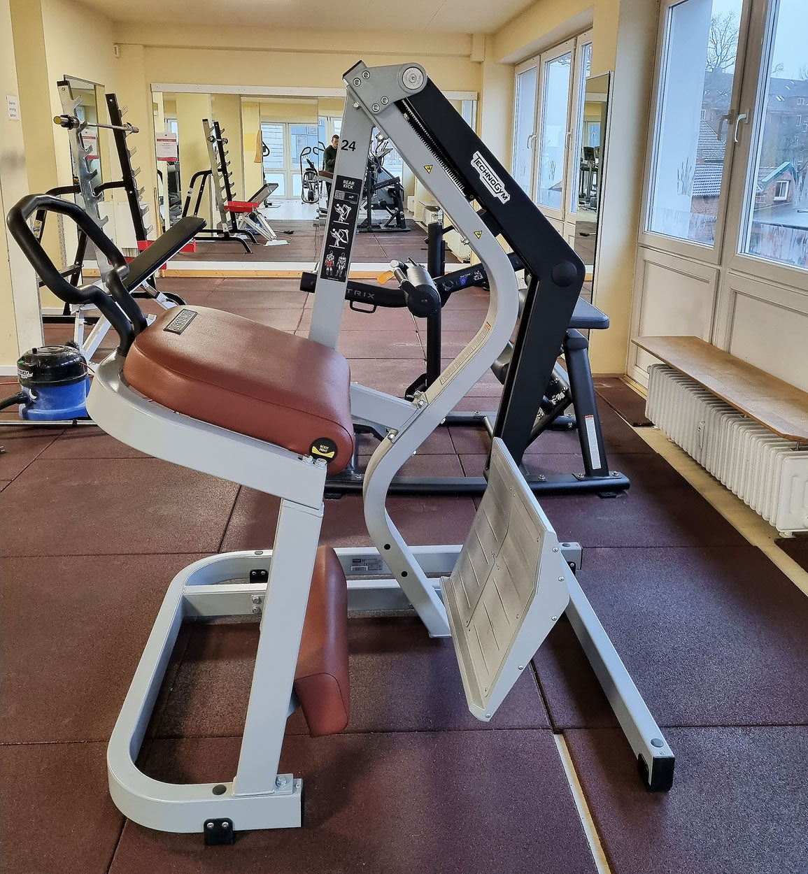 Technogym Pure Rear Kick, gluteus machine, butt machine standing, glute, plate loaded, Pure Strength Series disc holder, frame color silver, used - refurbished condition