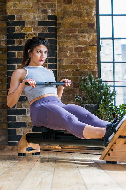 Person trainiert auf einem Rudergerät in einem Fitnessstudio.