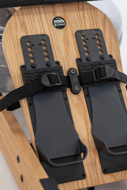 Rudergerät Fußstützen mit WaterRower Logo und Riemen.