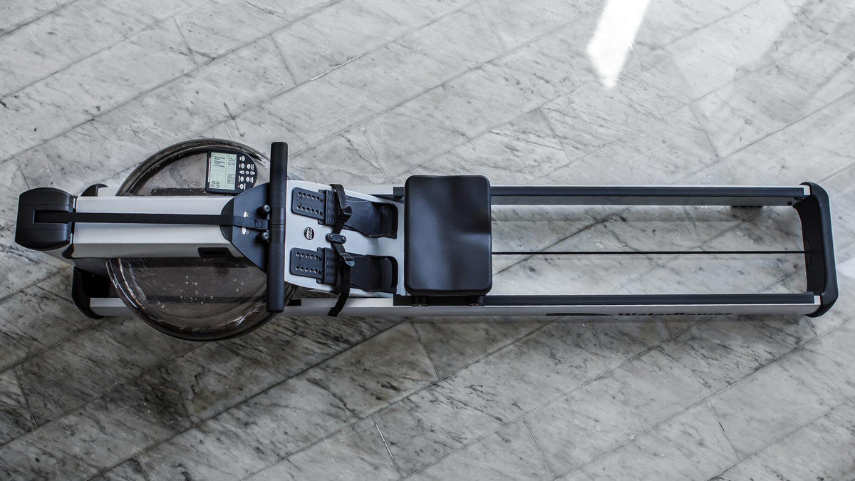 Rudergerät auf Marmorboden, Marke WaterRower, von oben fotografiert.