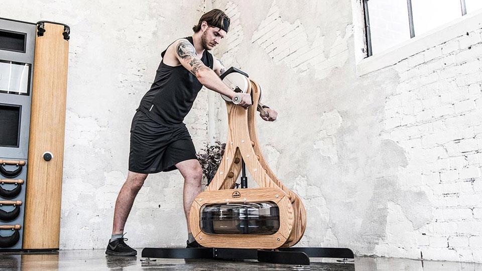 Person trainiert mit WaterRower Fitnessgerät in einem Raum.