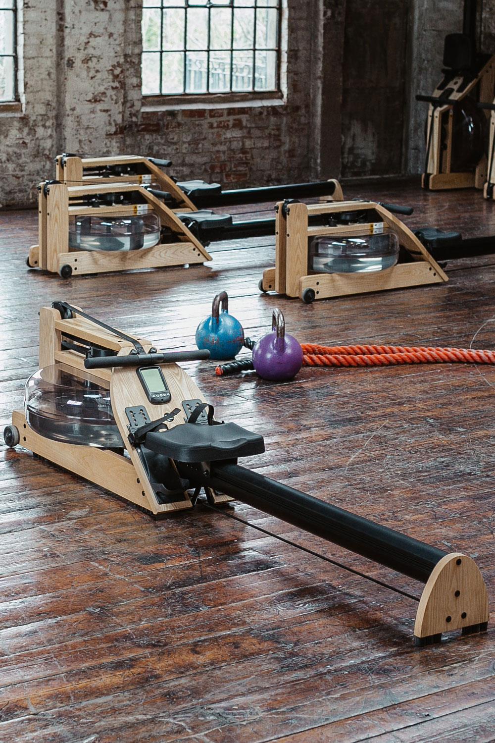 Rudergeräte, Kettlebells und Seil in einem Fitnessstudio.